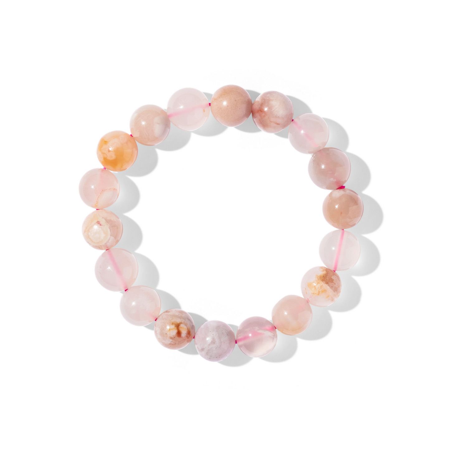 A single crystal gemstone bracelet made of sakura agate. A semi-transparent, shiny cream, pink, and yellow with ‘blossom’-like inclusions.