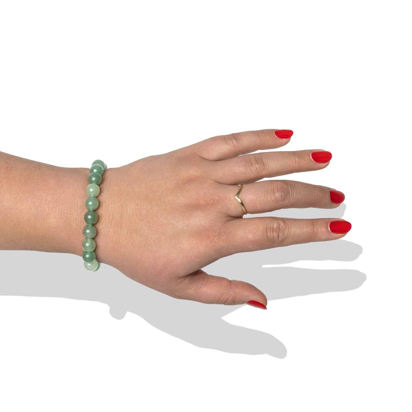 A single crystal gemstone bracelet made of green aventurine quartz, positioned on a hand with one gold ring and bright red nail polish.