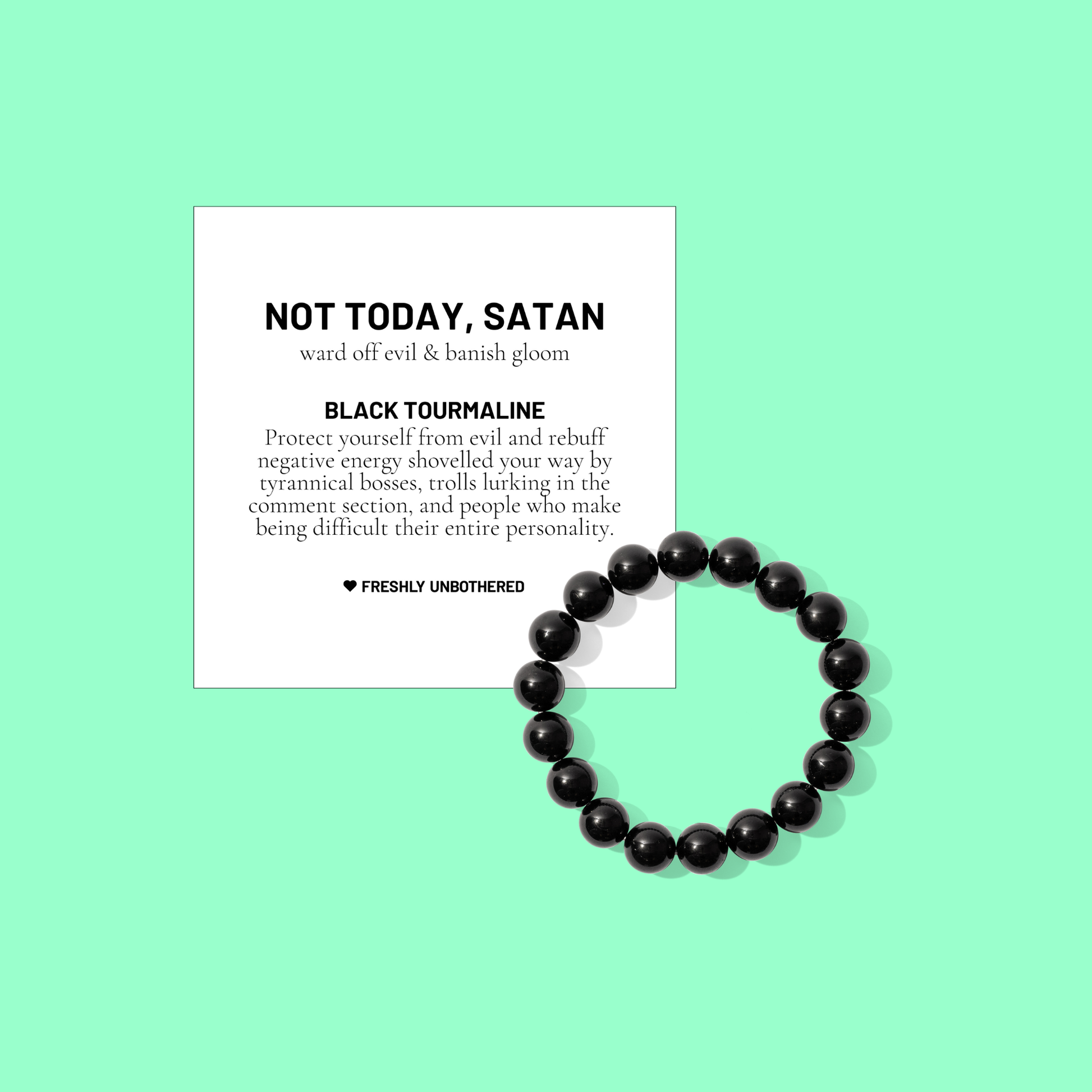 A green coloured background with a white card bearing the description of a crystal gemstone bracelet, and a round bead black tourmaline bracelet, positioned below and to the right of the card.