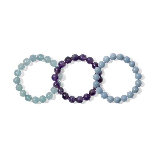 Three crystal gemstone bracelets on a white background. They are a mixture of light blue and purple colours.