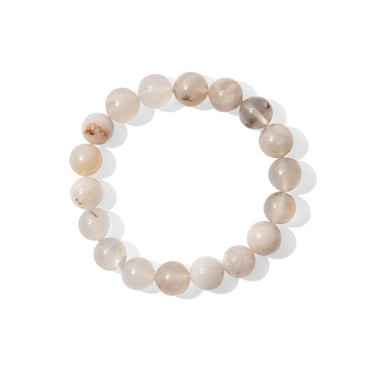 A single crystal gemstone bracelet made of sakura agate. A semi-transparent, shiny cream, pink, and yellow with ‘blossom’-like inclusions. 