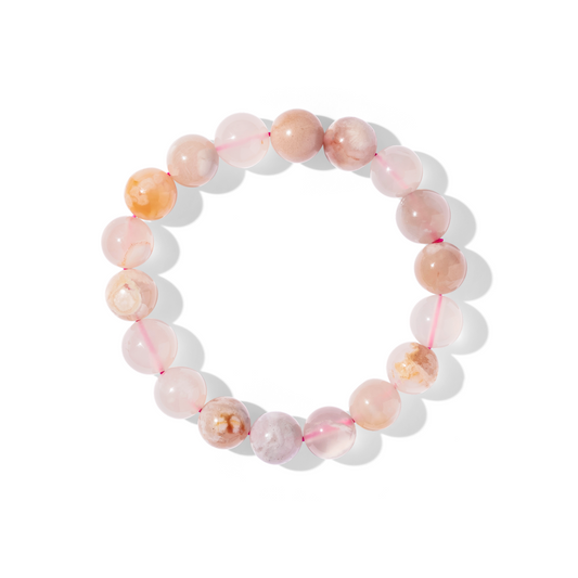 A single crystal gemstone bracelet made of sakura agate. A semi-transparent, shiny cream, pink, and yellow with ‘blossom’-like inclusions. 