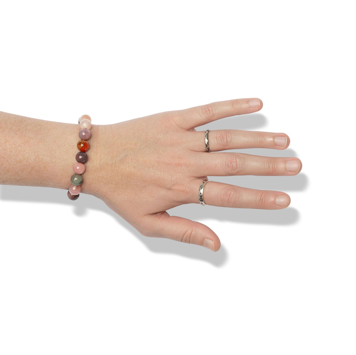 A single crystal gemstone bracelet made of Yanyuan candy agate, positioned on a hand adorned with two silver rings.