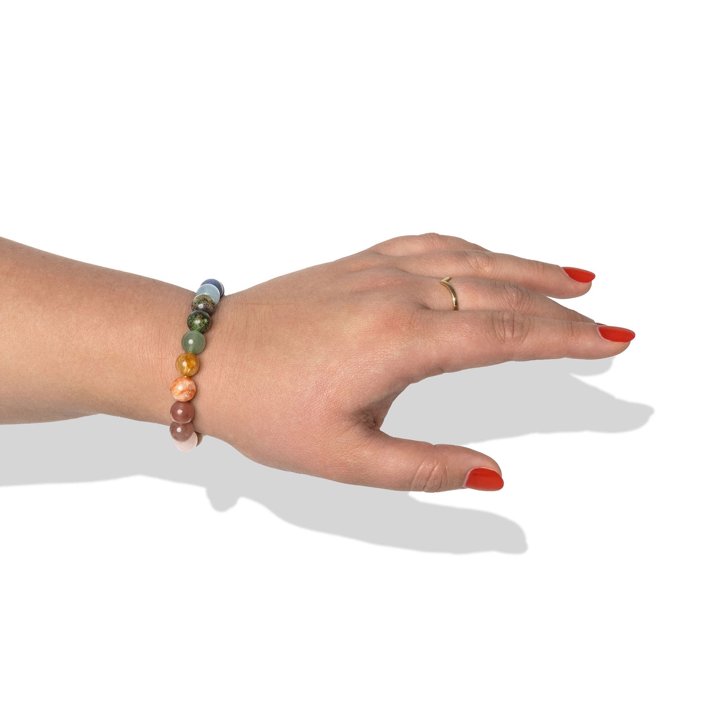 A single crystal gemstone bracelet made of different muticoloured beads, positioned on a hand with one gold ring and bright red nail polish.