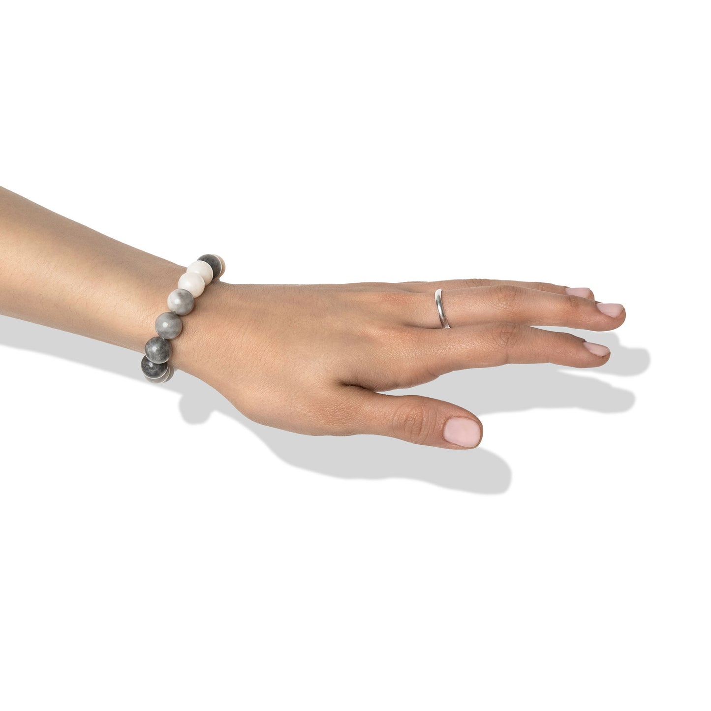 A single crystal gemstone bracelet made of hawk's eye, positioned on a hand adorned with a silver ring and light pink nail polish.