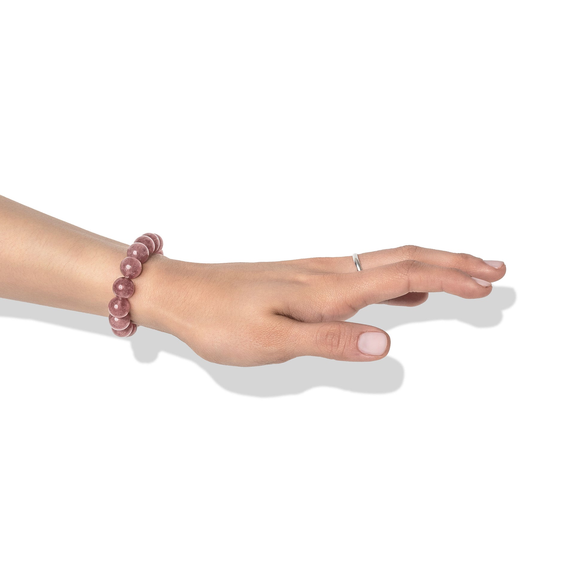 A single crystal gemstone bracelet made of strawberry quartz, positioned on a hand adorned with a silver ring and light pink nail polish.